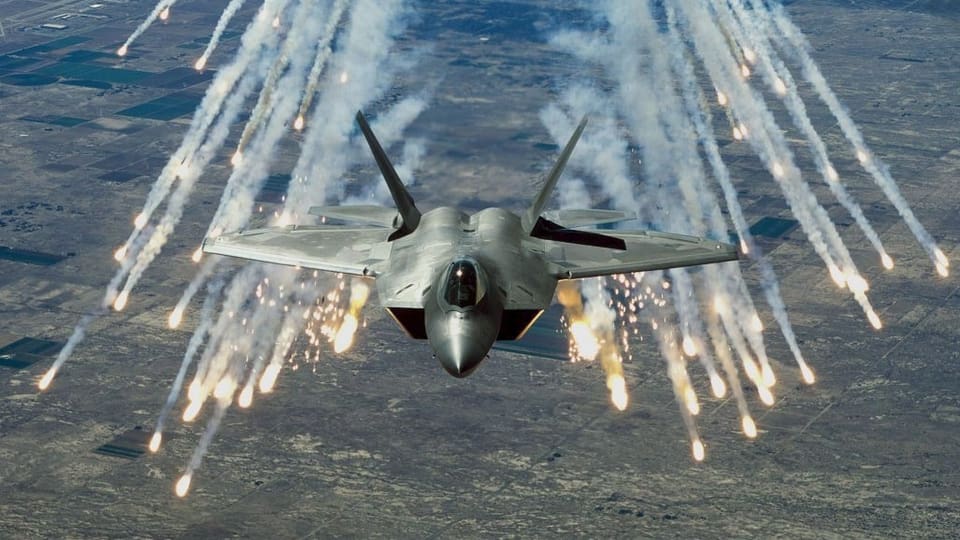 Ein Kampfjet feuert hell aufblitzende Flugkörper ab