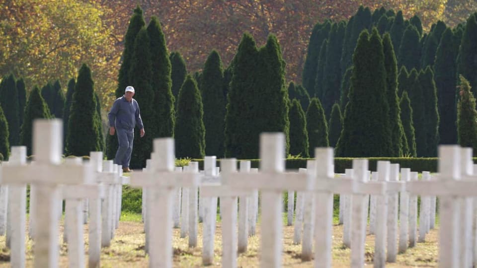 Stjepan Vidakovic läuft auf einem Friedhof an weissen Kreuzen entlang.