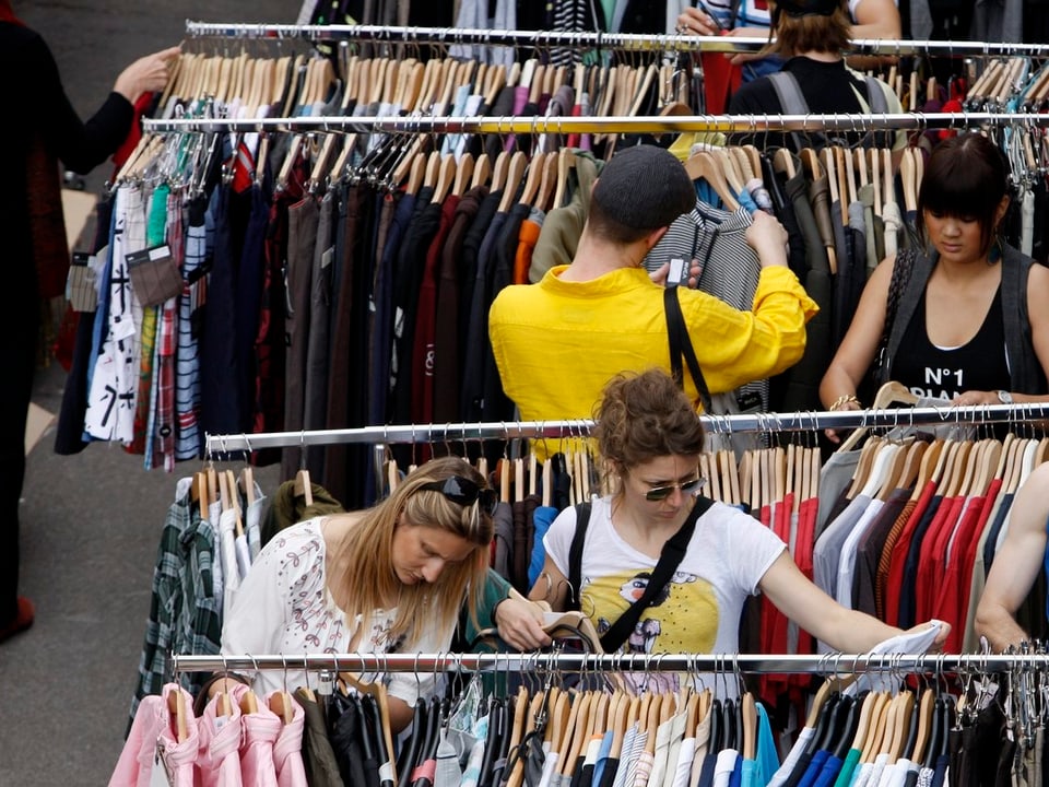 Menschen suchen nach einem Kleidungstück in einem Kleiderladen