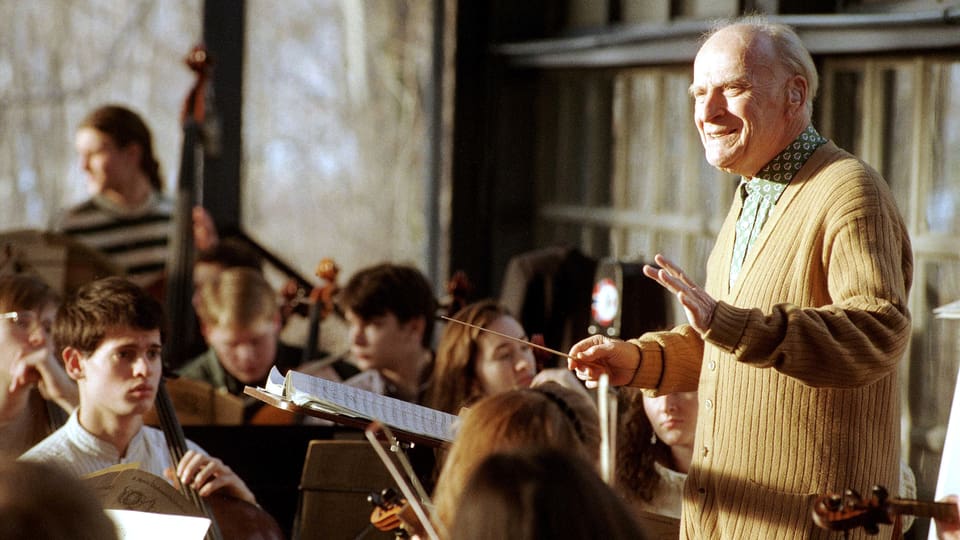 Ein älterer Herr dirigiert stehend ein Jugendorchester.