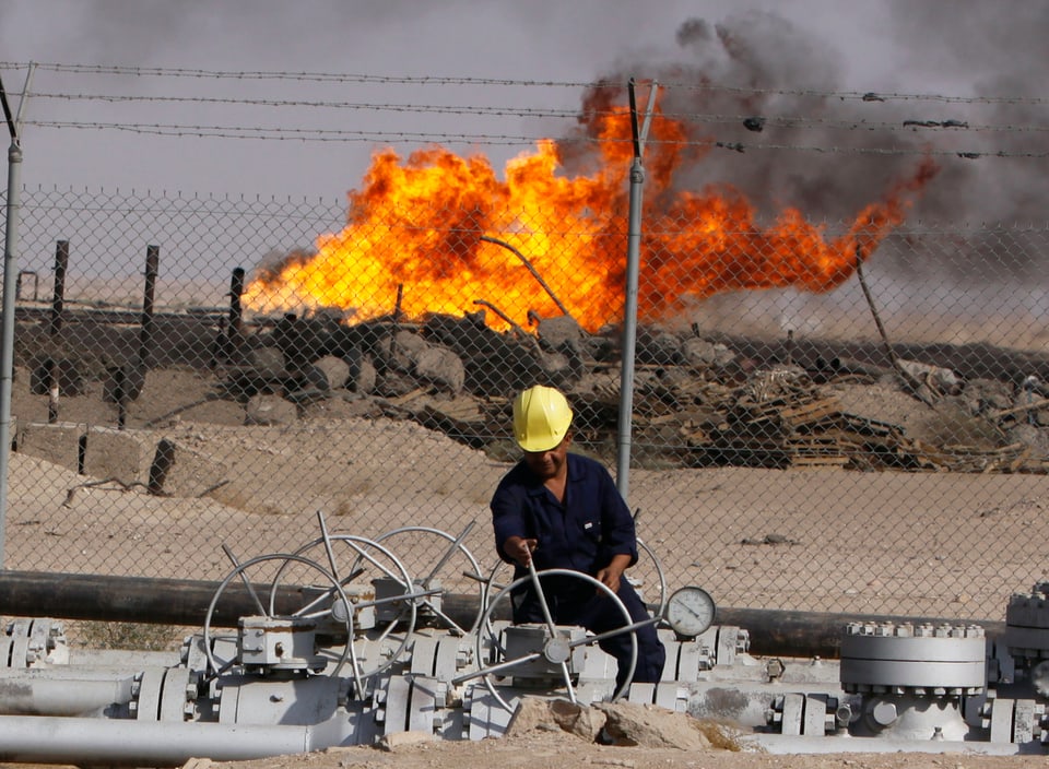 Mann in gelbem Helm bei der Arbeit auf einem Ölfeld in der Wüste.