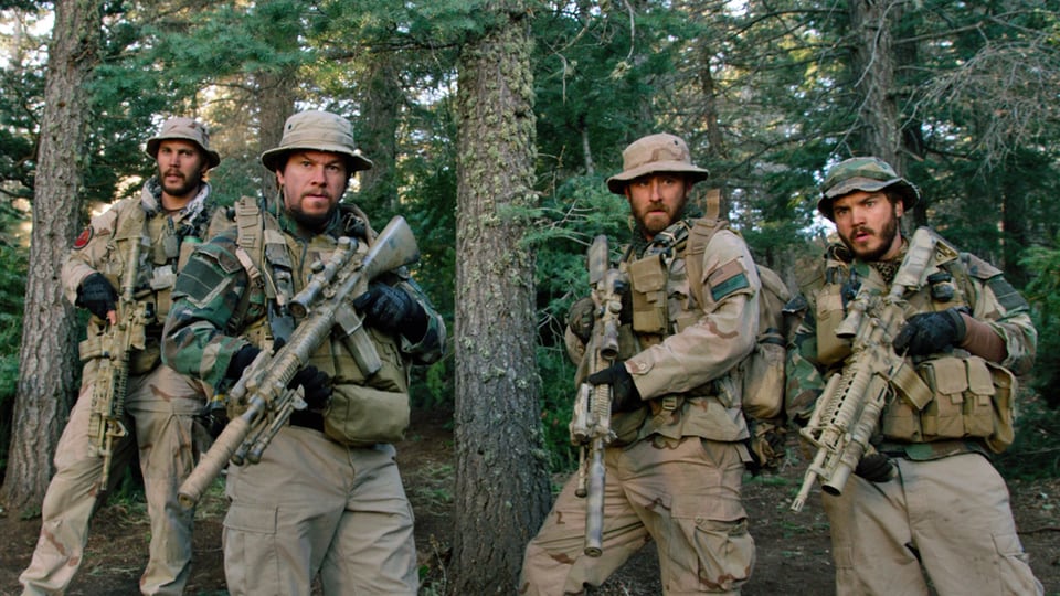 Vier Männer in Armeeuniformen mit Gewehren.