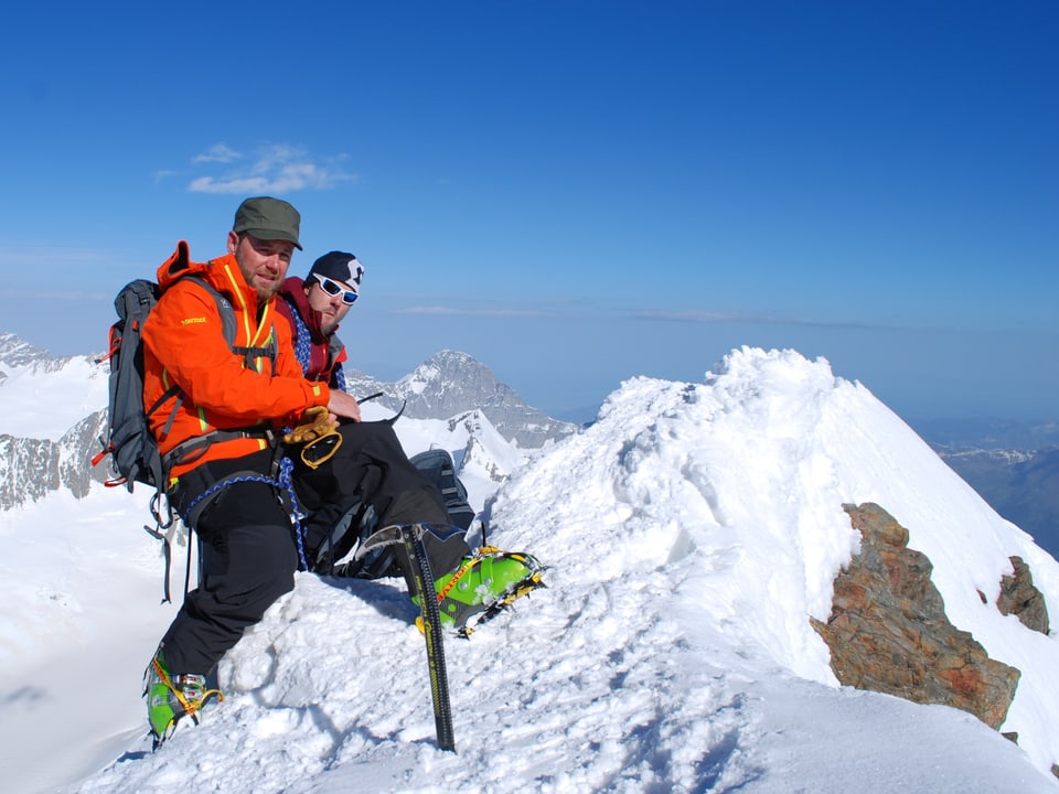 Nik Hartmann und Bergführer ruhen sich auf dem Gipfel des Finsteraarhorns aus. 