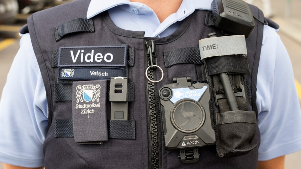 Weste einer Polizistin mit einer Bodycam, Funk und Abzeichen dran