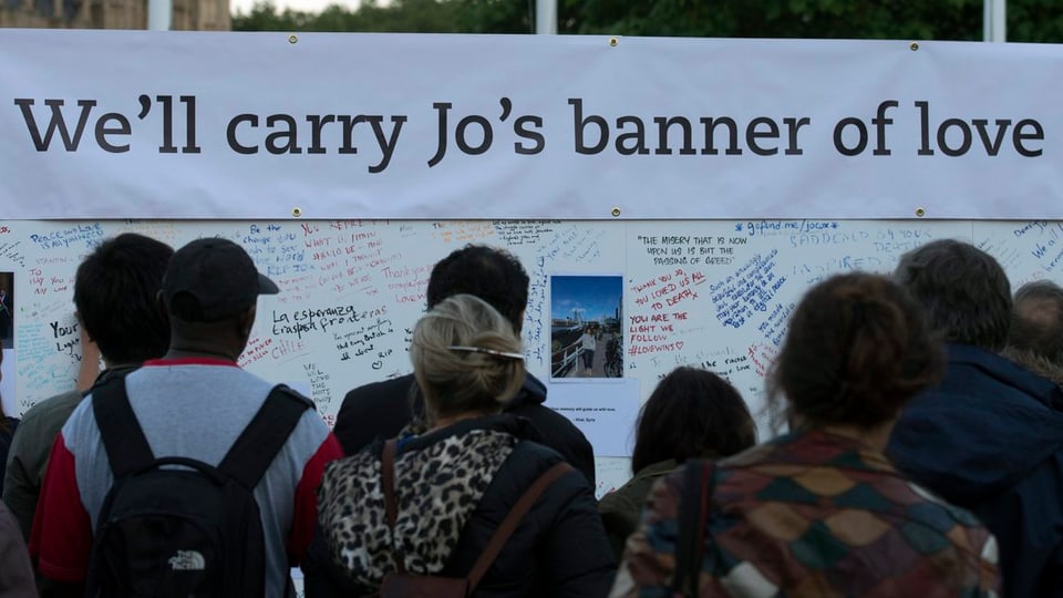 Menschen vor einem Plakat versammelt mit der Aufschrift: «We'll carry Jo's banner of love»