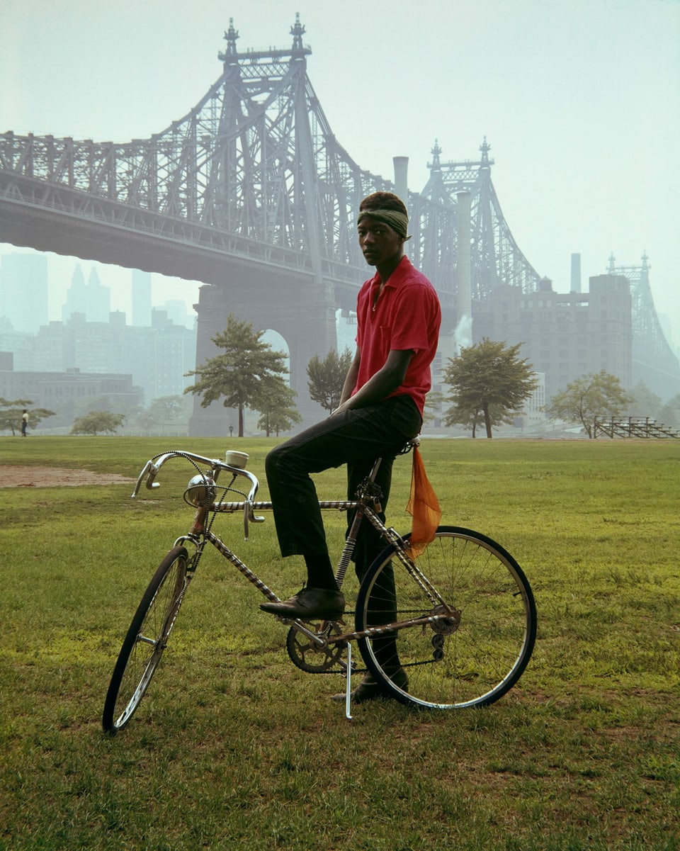 Ein schwarzer Junge posiert auf seinem Rennrad vor der Queensborough Bridge in New York.