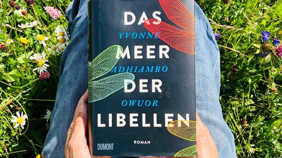 Das Buch «Das Meer der Libellen» von Yvonne Adhiambo Owuor liegt auf Annette Königs Knien