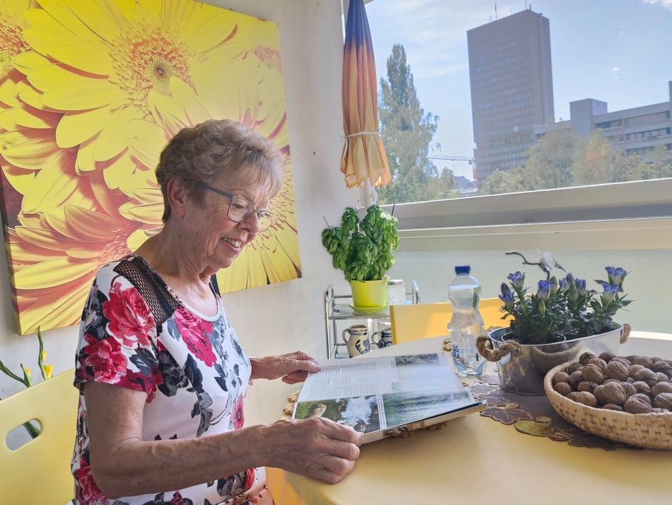 Ältere Dame liest Zeitschrift an einem Tisch in Wintergarten