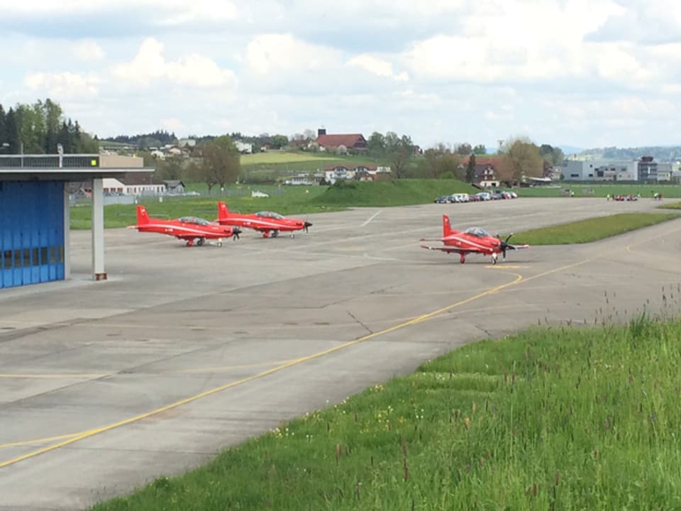 Drei rote Flugzeuge stehen auf einem Rollfeld.
