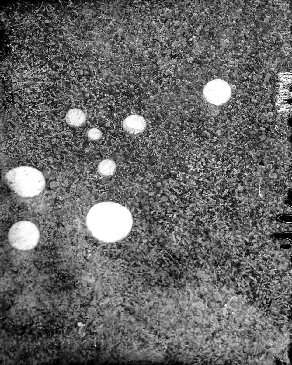 Schwarz-Weiss-Aufnahme eienr Oberfläche, auf der sich weisse Kugeln befinden. 