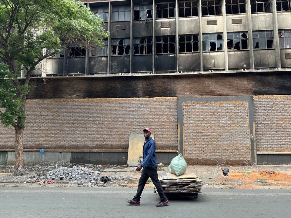 Ein Mann läuft an ausgebranntem Gebäude vorbei