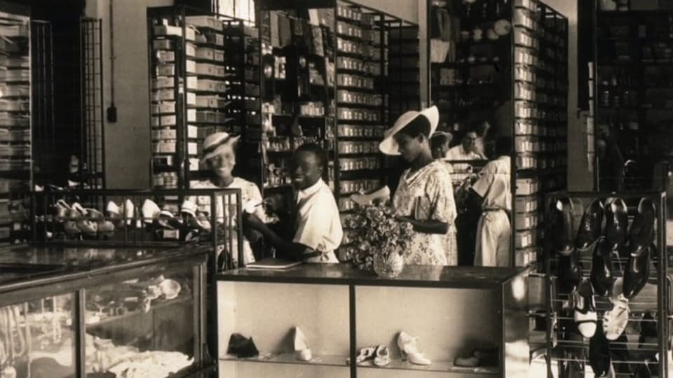 Schwarzweissfoto: Schuhladen mit dunkelhäutigen Kundinnen und Kunden