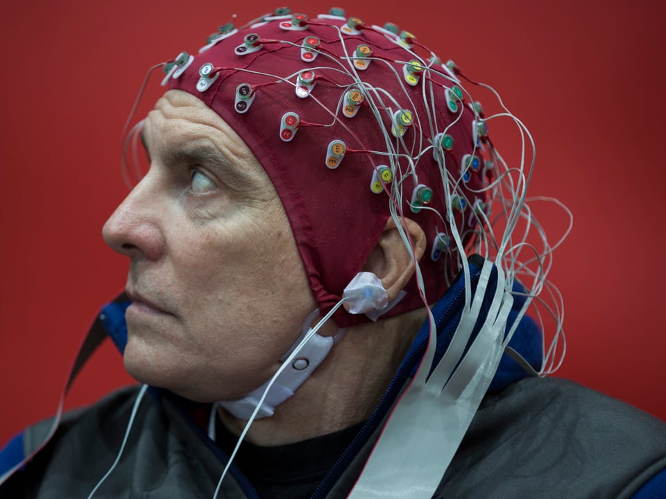 Ein Mann trägt ein Haube mit Elektroden, die seine Gehirmströme messen.