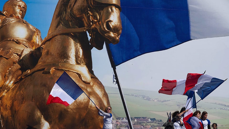 Ein goldenes Pferd und Frankreich-Flaggen werden während einer Veranstaltung von Anhängern des Front National hochgehalten.