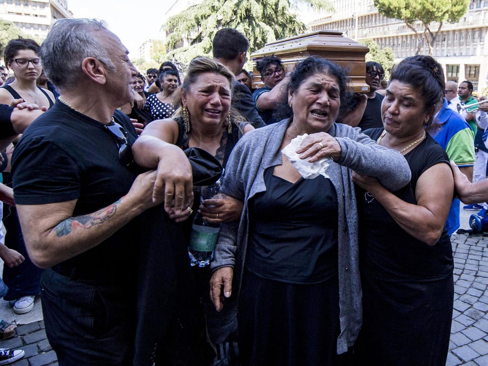 Menschen nehmen an einem Beerdigungsumzug teil, sie trauern.