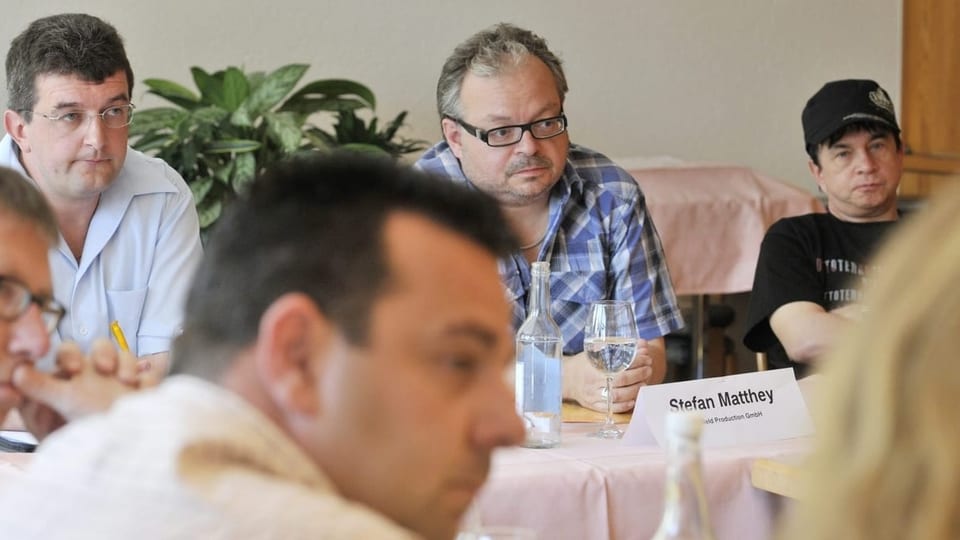 Männer sitzen am Tisch bei einer Medienkonferenz.
