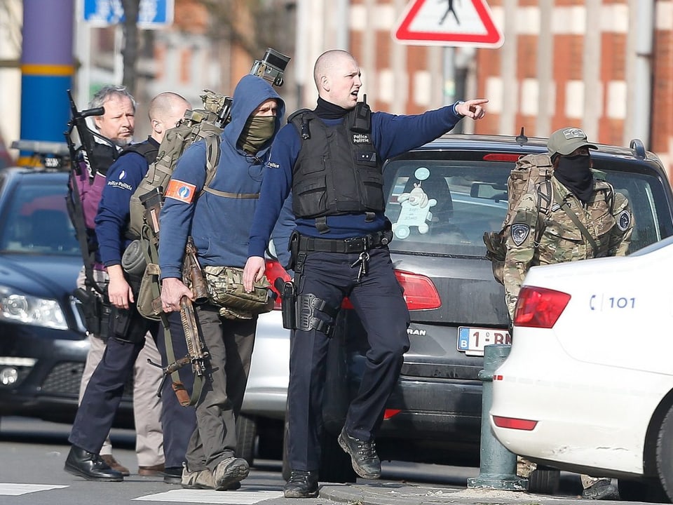 Ein Polizeibeamter zeigt mit dem Finger auf einen Ort in der Ferne, mehrere bewaffnete Kollegen folgen ihm