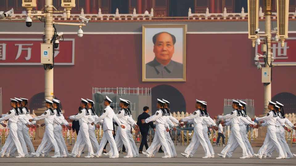 Matrosen defilieren vor einem Bild von Mao Zedong vorbei.