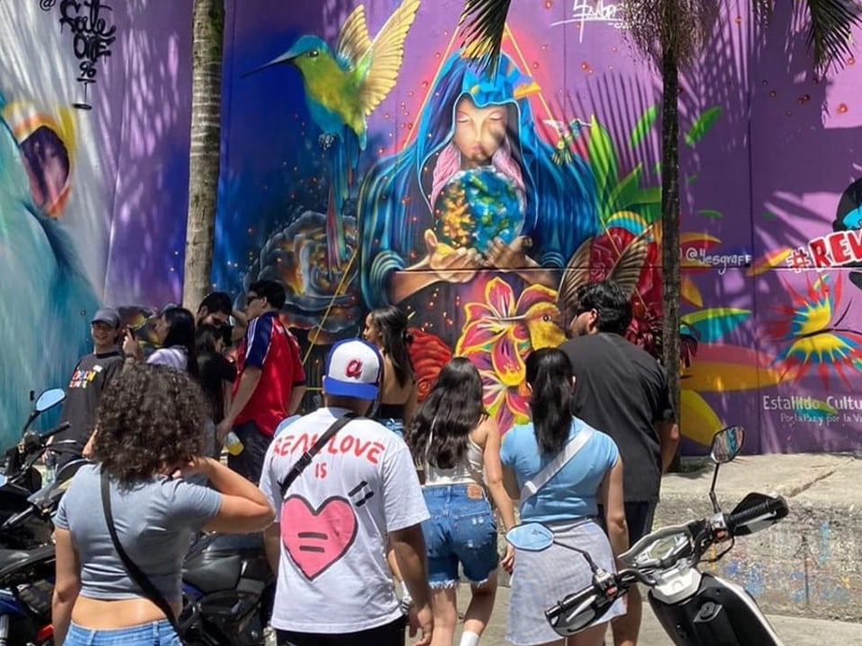 People see colorful street graffiti with hummingbirds and earth globes.