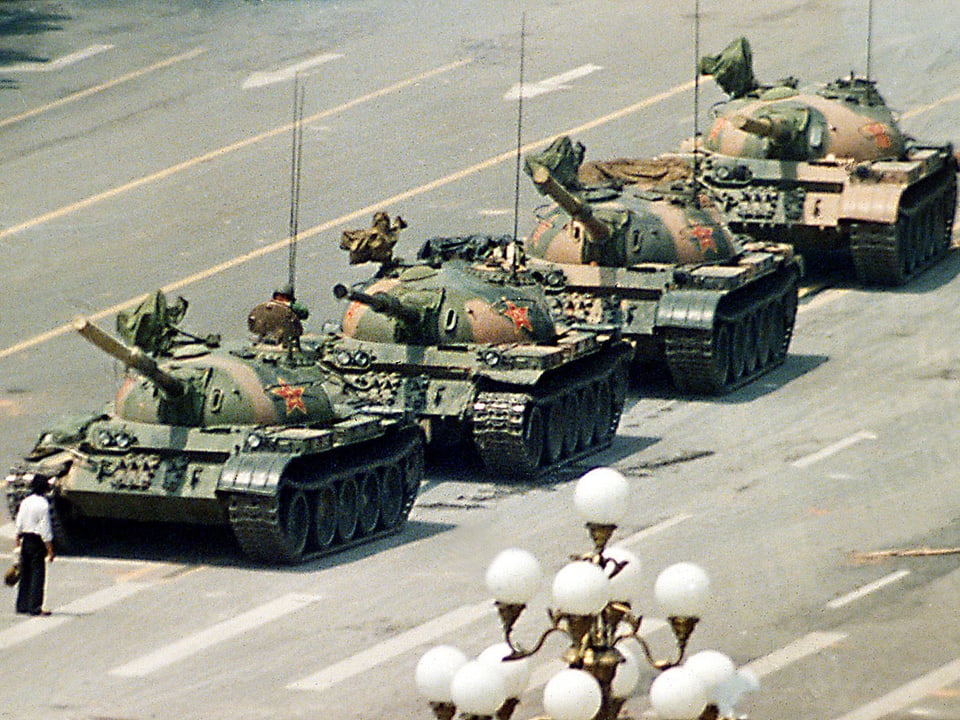 Ein Mann steht ganz alleine vor vier Panzern.