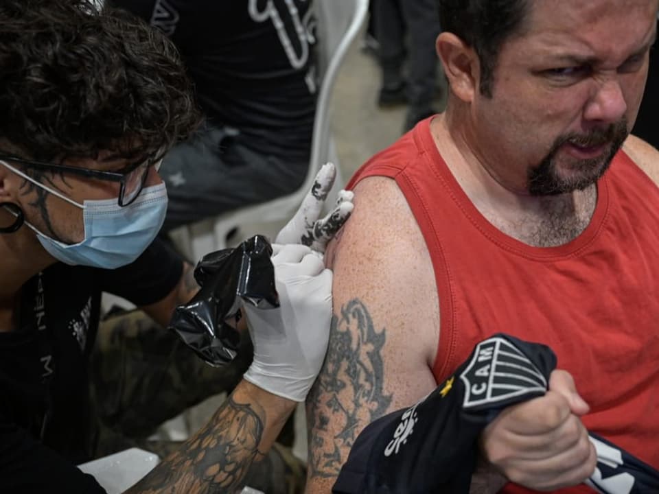 Auf den rechten Oberarm eines Mannes wird ein Tattoo gestochen.