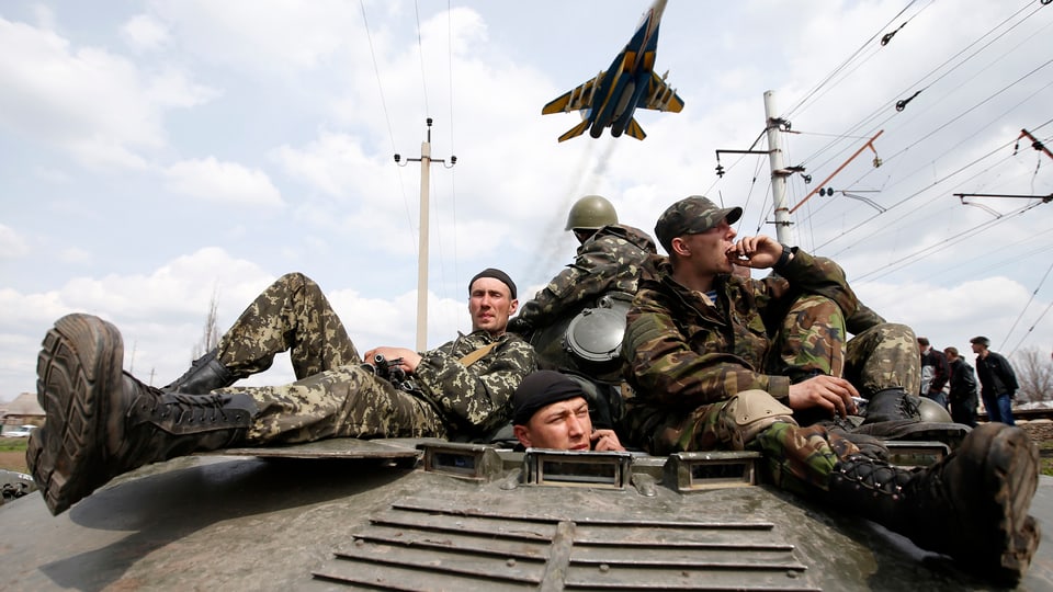 Ukarinische Soldaten sitzen auf einem Panzer und strecken ihre Beine