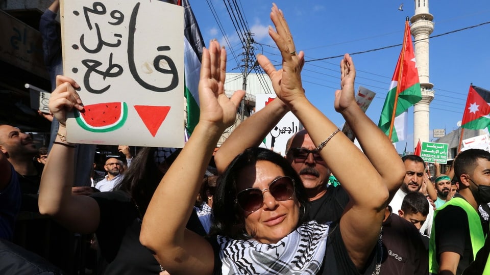 Protest mit jordanischen Flaggen und pro-palästinensischen Schildern. Die Frau im Vordergrund trägt eine Kuffiyeh.