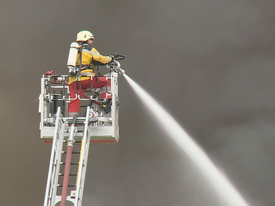 Ein Feuerwehrmann spritzt mit einem Schlauch Wasser.