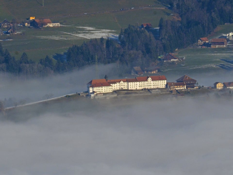 Blick vom Planggenstock zum Kloster Berg Sion, das knapp aus dem Nebel herausragt.