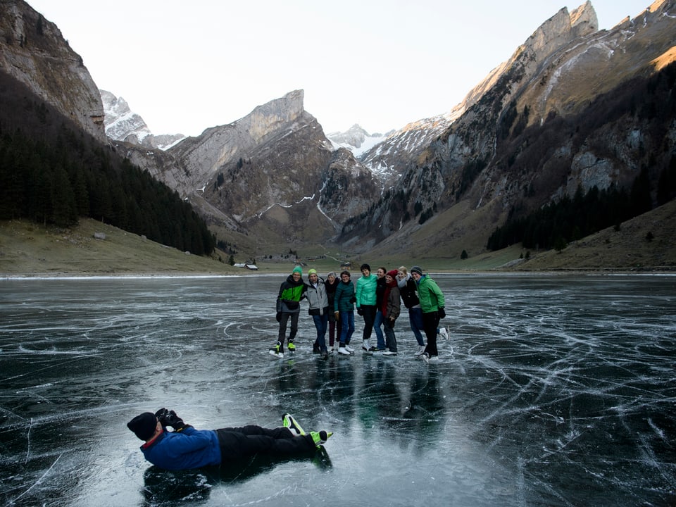 Eine Person fotografiert eine Gruppe Schlittschuhläufer auf dem gefrorenen See.