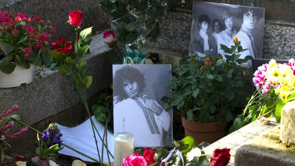 Ein Grab bedeckt mit Blumen und Fotos von Jim Morrison.