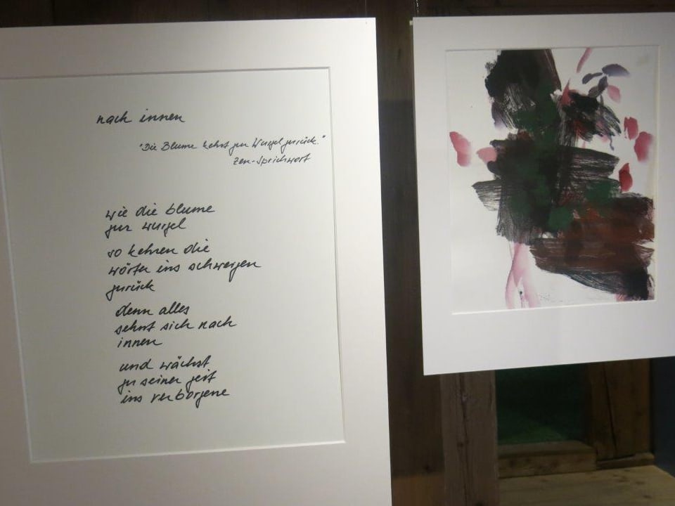 Eine Tafel mit einem Gedicht, daneben ein Bild - Beides hängt im Raum.