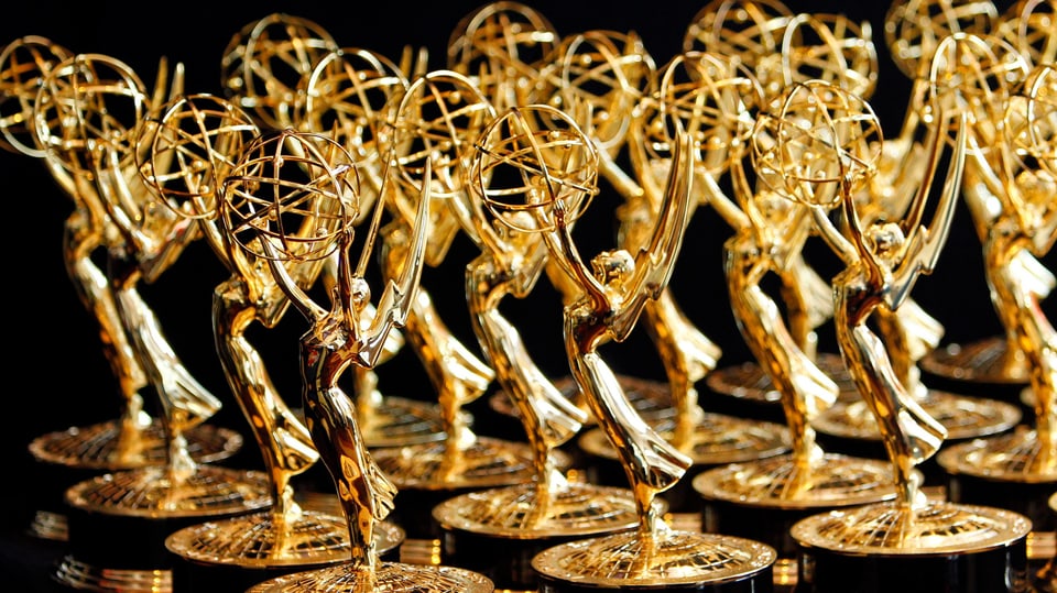 Mehrere Emmys in einer Reihe auf einem Tisch.