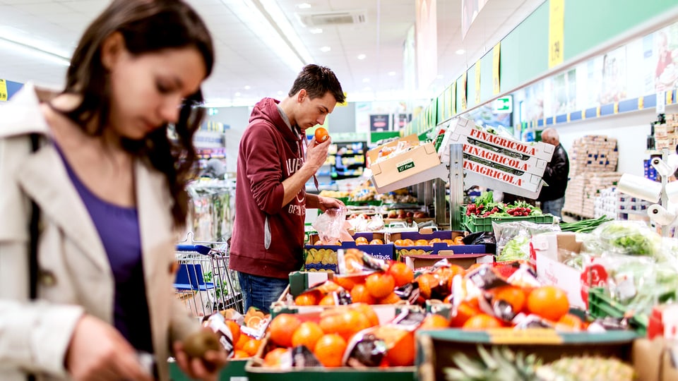 Eine Frau und ein Mann stehen vor der Früchteauslage im Supermarkt. 