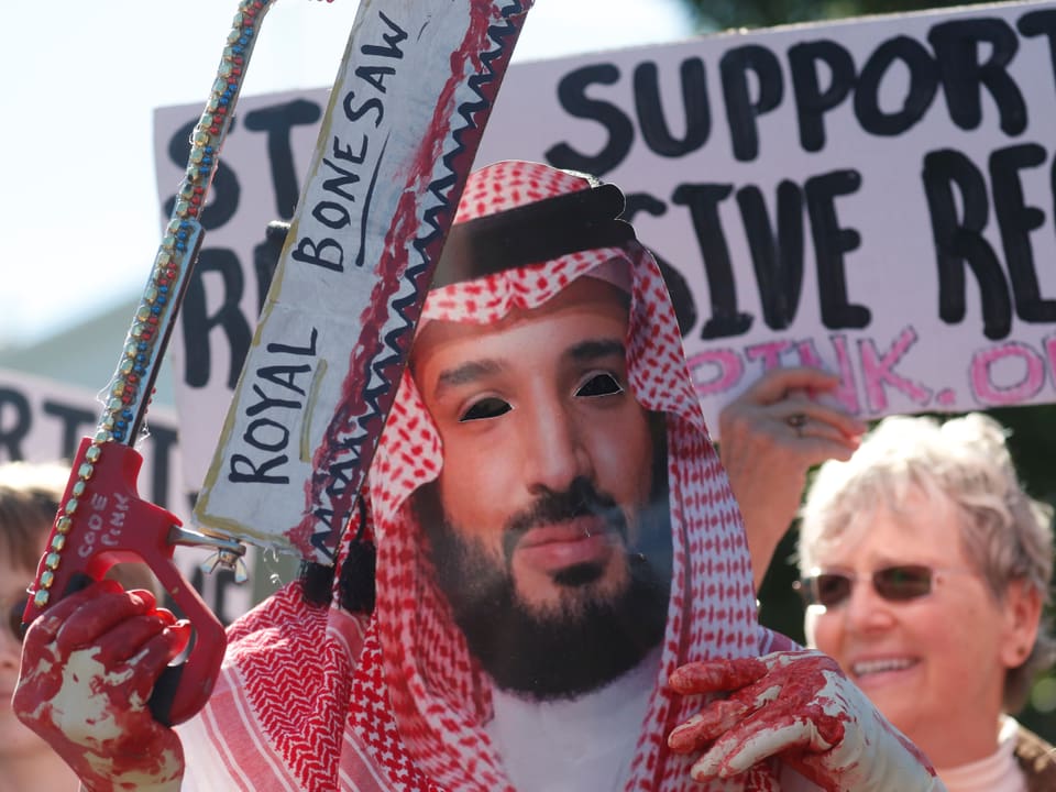 Demonstration. Ein Mann verkleidet als Kronprinz Salman hält eine blutige Säge.