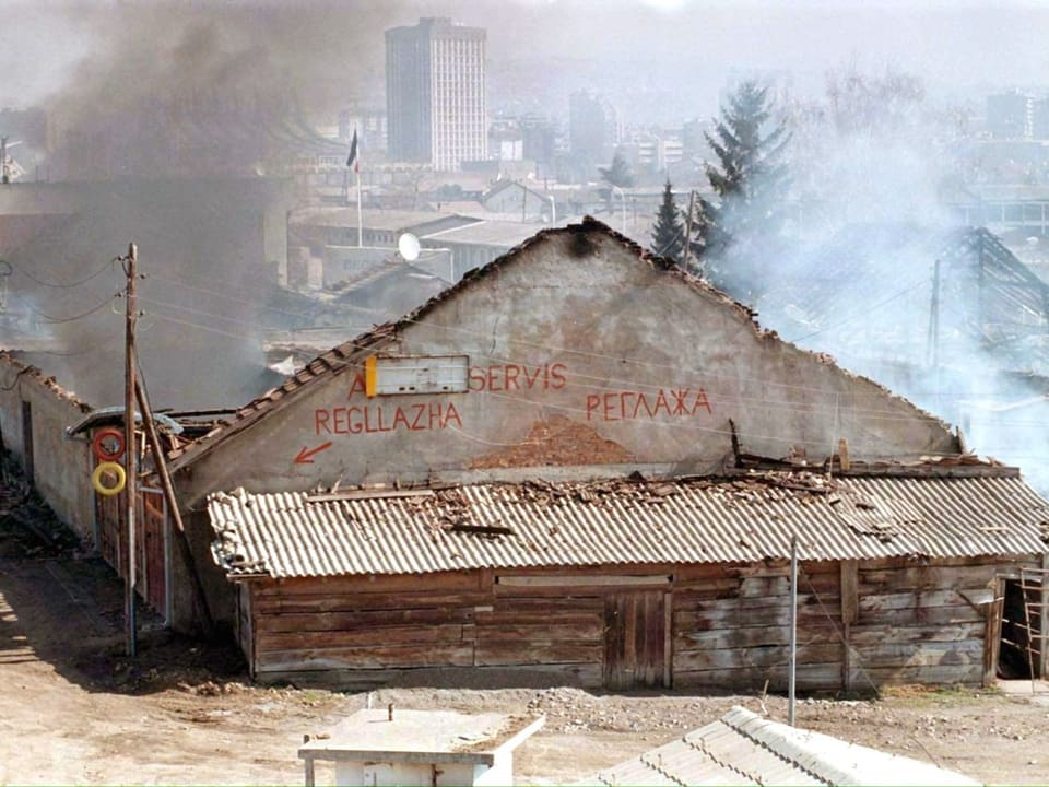 Ein zerbombtes Gebäude, rauch steigt auf. 