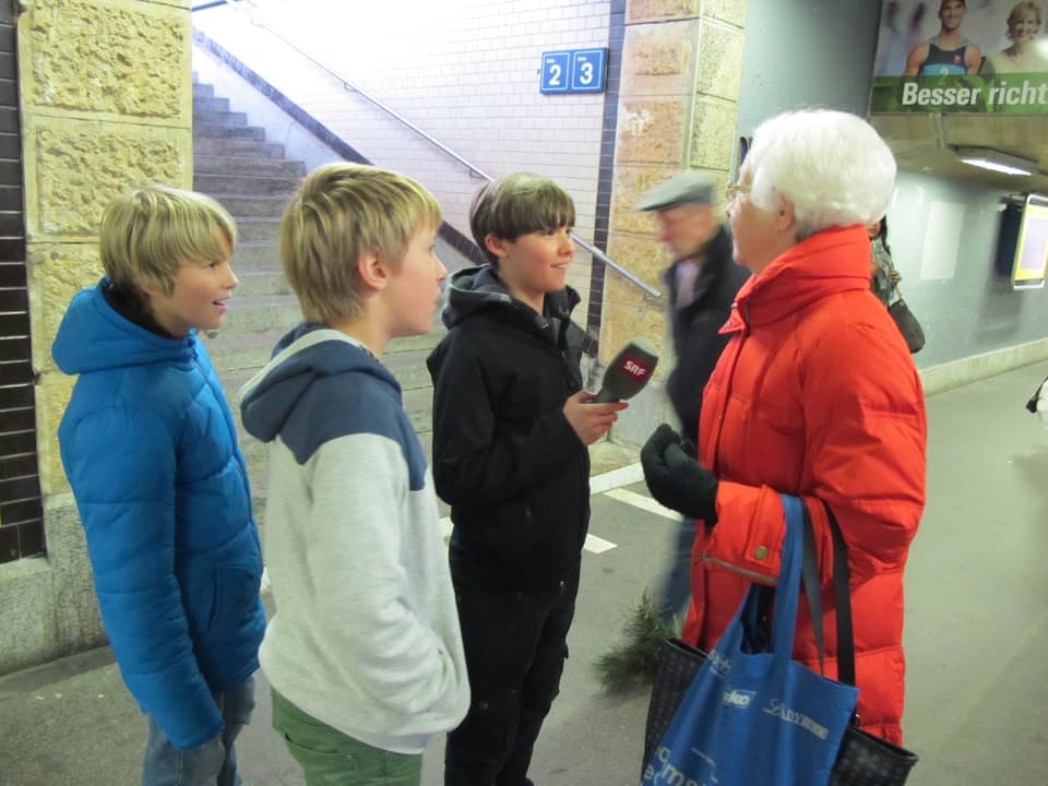 Kinder interviewen in der Bahnhofsunterführung eine Passantin.