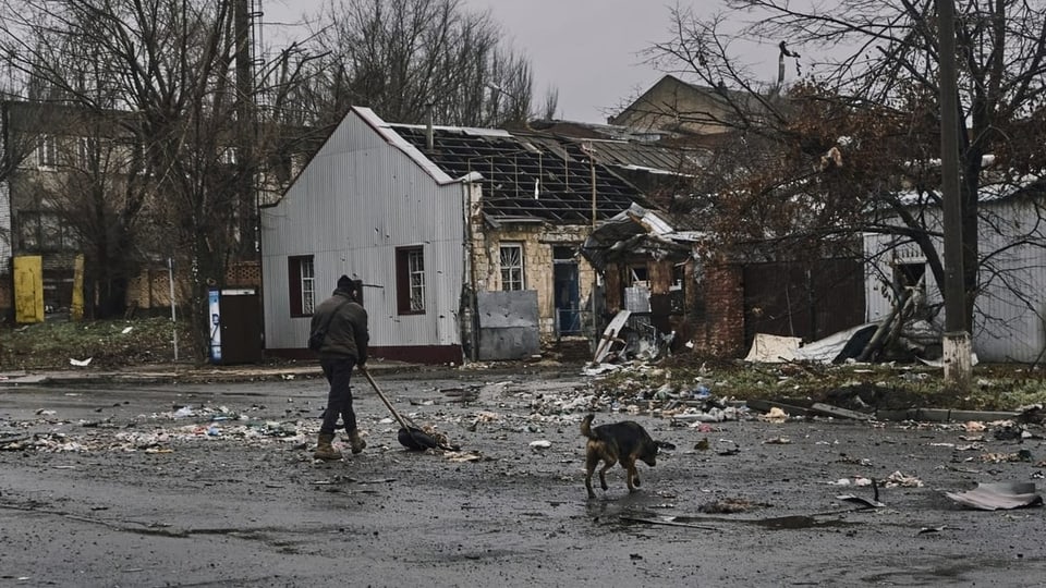 Ein Einwohner reinigt die Strasse nach russischem Beschuss in Bachmut