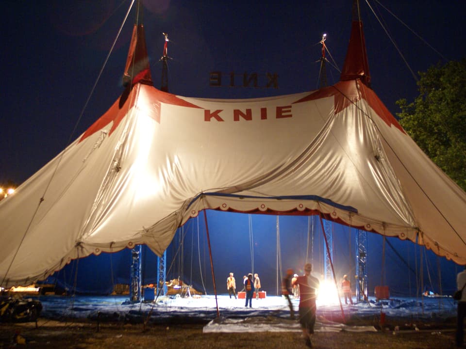 Arbeiter bauen im Schweinwerferlicht ein Zirkuszelt auf
