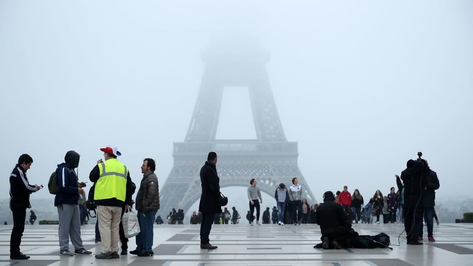 Menschen, einer mit Gelbweste, vor dem Eiffelturm