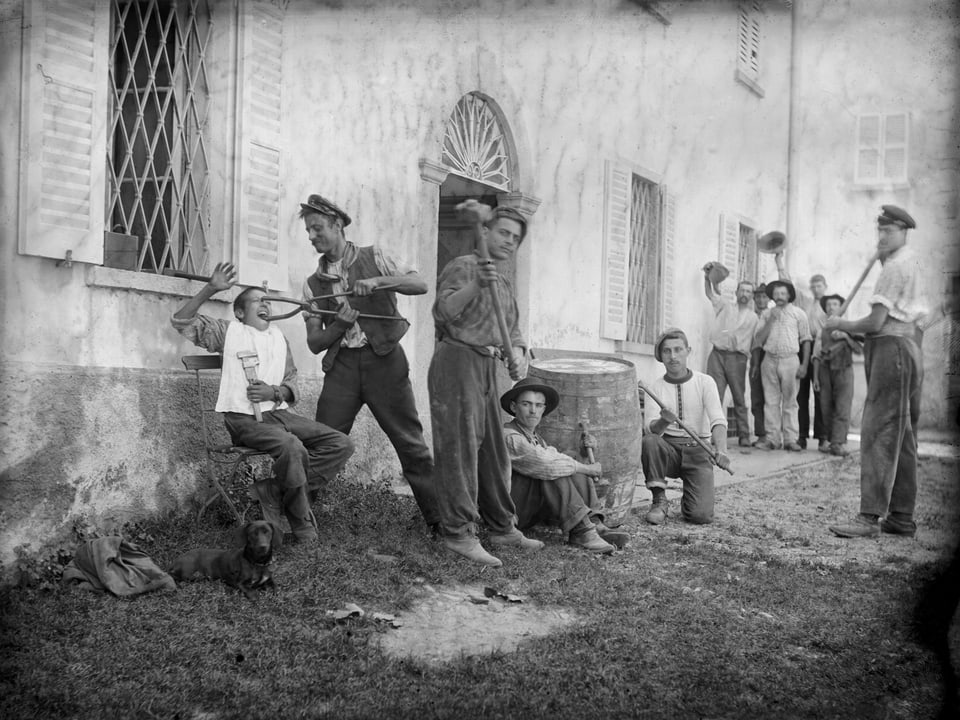 Männer mit Hammer und Zange beim humoristischen Spiel vor einer alten Fabrik.