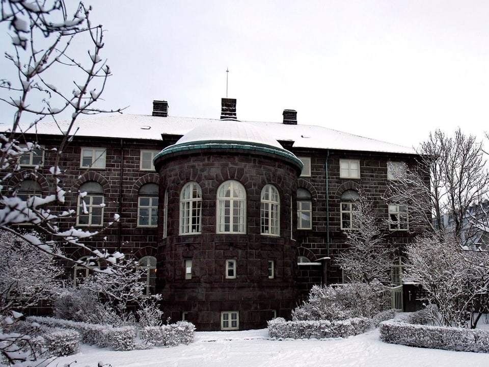 Das isländische Parlamentsgebäude in Rejkjavik mit schneebedecktem Dach.