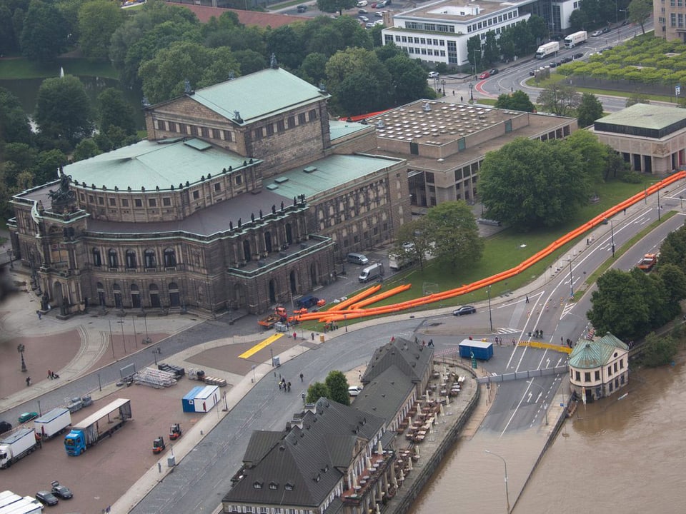 Luftaufnahme der Semperoper. Davor mobile orange Hochwassersperren. Im Vordergrund die Elbe, die schon die Strasse überflutet hat.