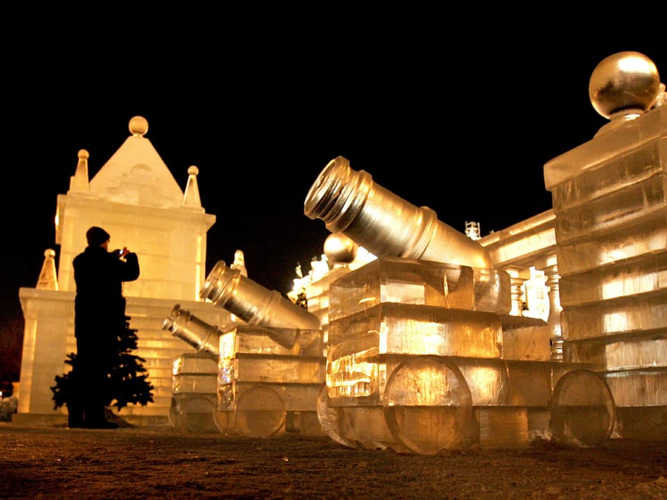 Drei beleuchtete Kanonen aus Eis vor einem Eispalast in der russischen Stadt Sankt Petersburg.