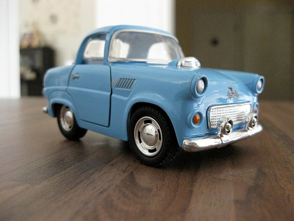 Ein hellblaues Spielzeugauto steht auf einem Holztisch.