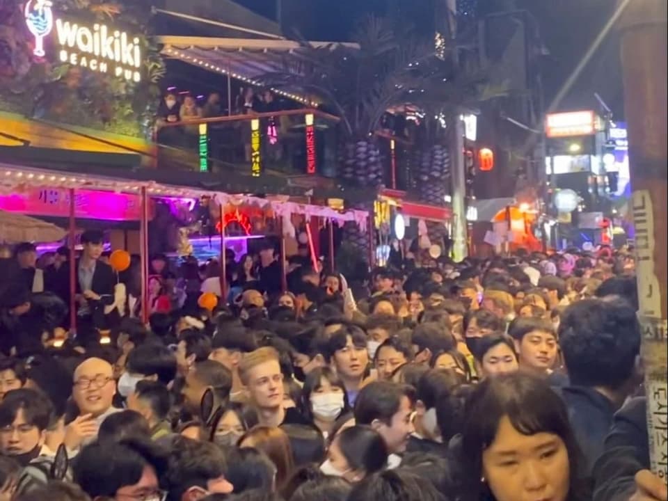 Aufnahme einer Gasse im besagten Ausgehviertel in Seoul. Menschen stehen dicht gedrängt in der Gasse.