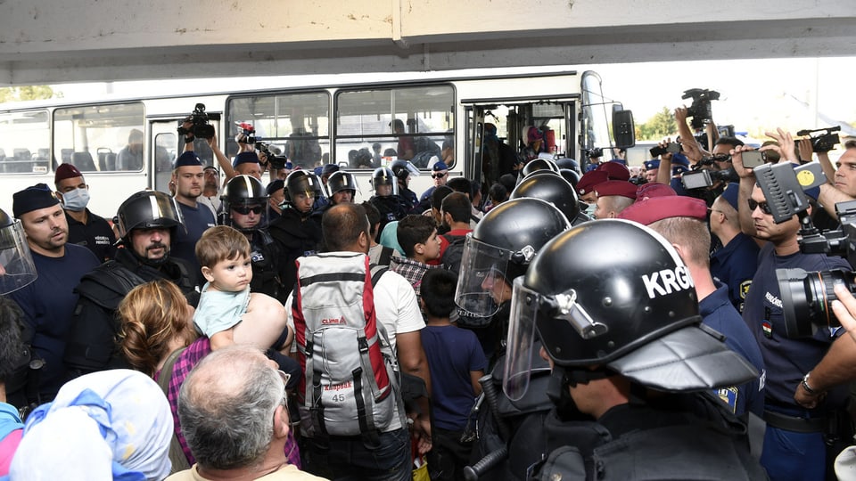 Flüchtlinge werden in einen Bus gelotst.