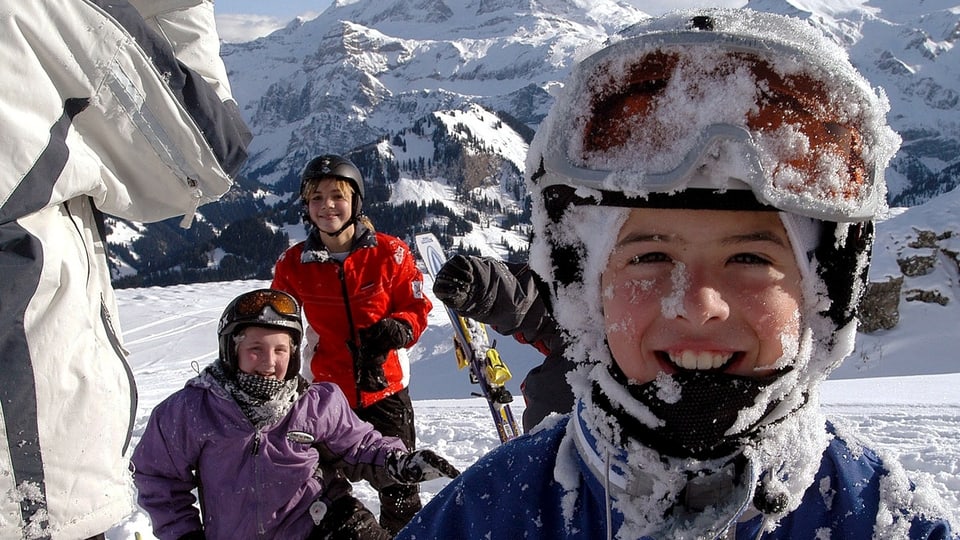 Kinder im Skigebiet blicken in die Kamera.