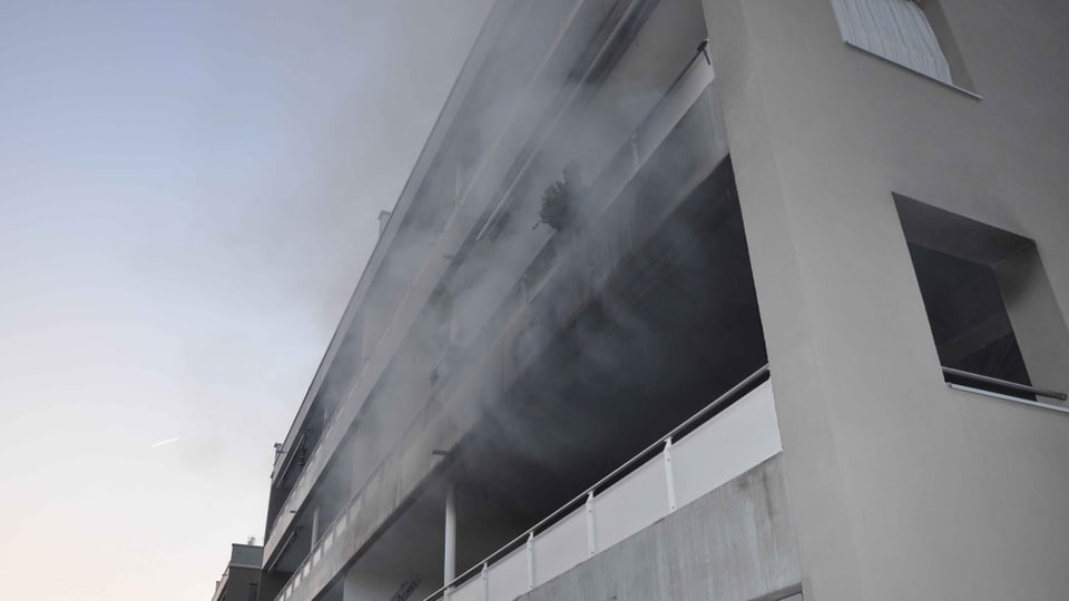 Rauch kommt aus einem Balkon bei einem Wohnblock