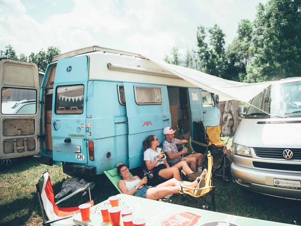 Ein Camper und davor sind Menschen, die entspannen